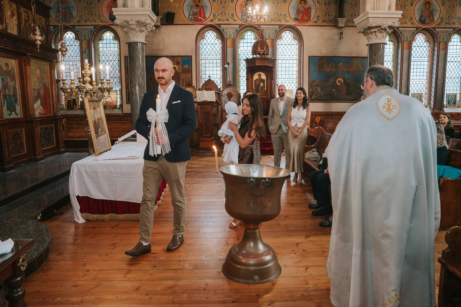  Godfather walking with decorated baptism candle during the service at St Constantine &amp; St Helen Greek Orthodox Church, SE19. 