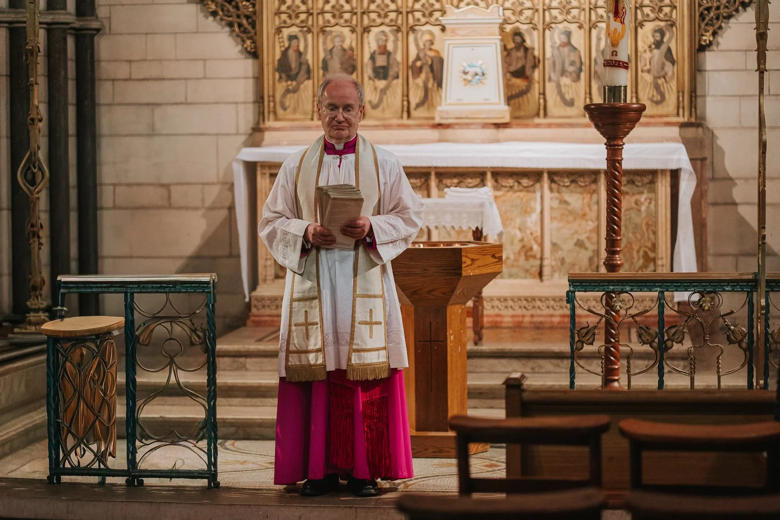 Catholic priest standing at the altar inside St James’ Catholic Church Spanish Place London during a christening ceremony. 