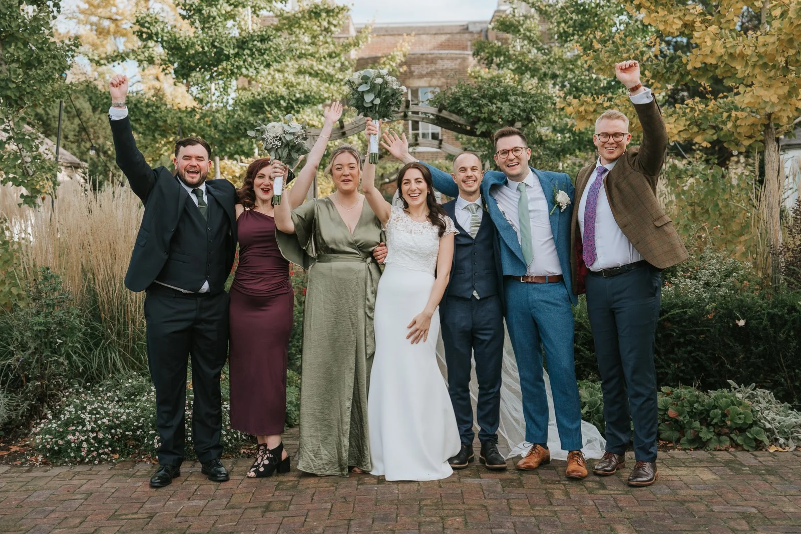  Bride and groom celebrating with wedding party in the gardens at Morden Park House, South London wedding venue, relaxed documentary wedding photography with natural candid moments 