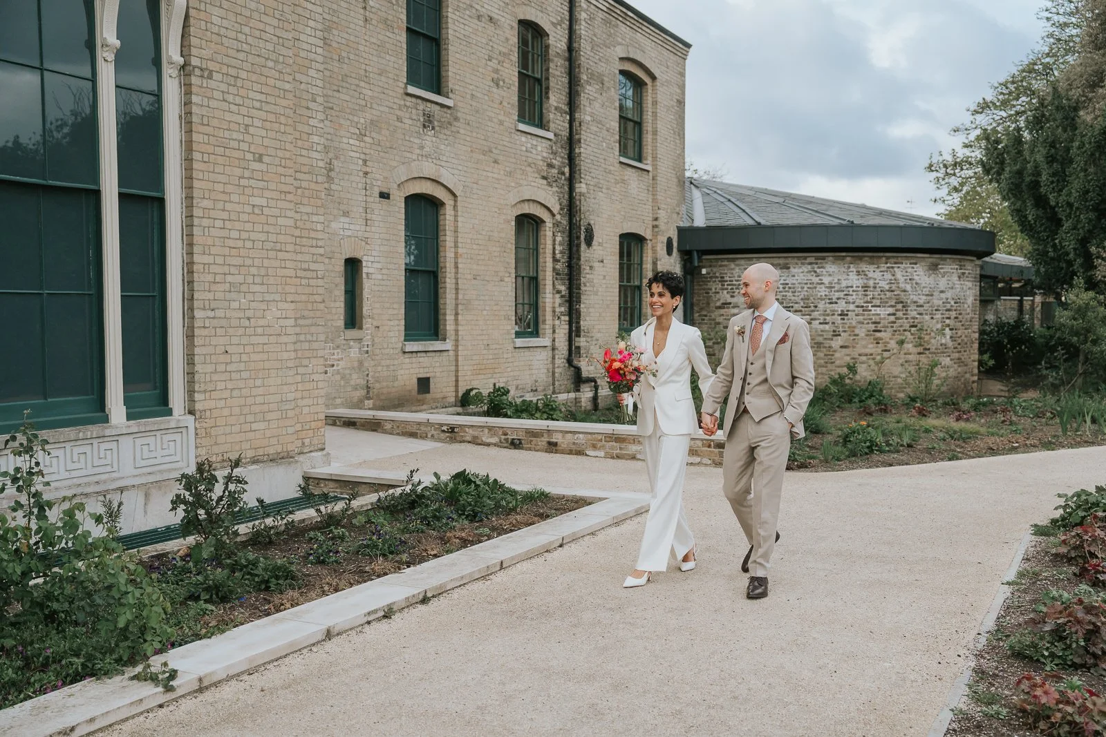  Bride and groom walking past Brockwell Hall gardens, natural documentary wedding photography at Brockwell Park South London venue. 