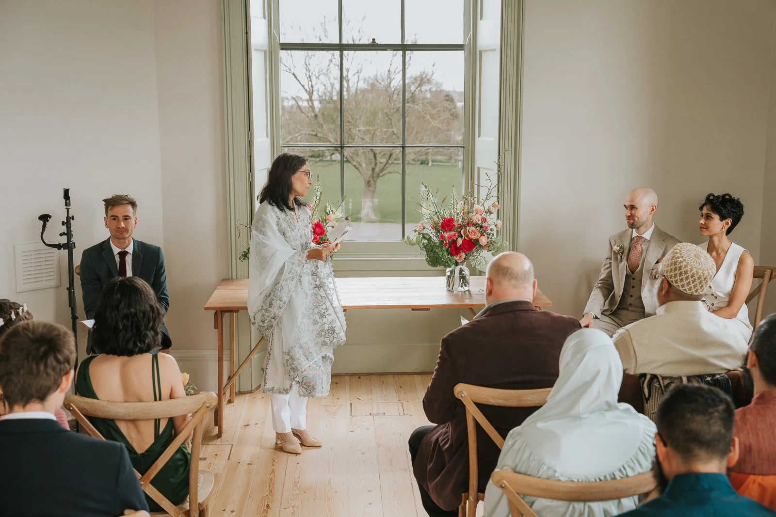  Wedding ceremony reading at Brockwell Hall with large windows overlooking Brockwell Park, relaxed South London civil ceremony setting. 
