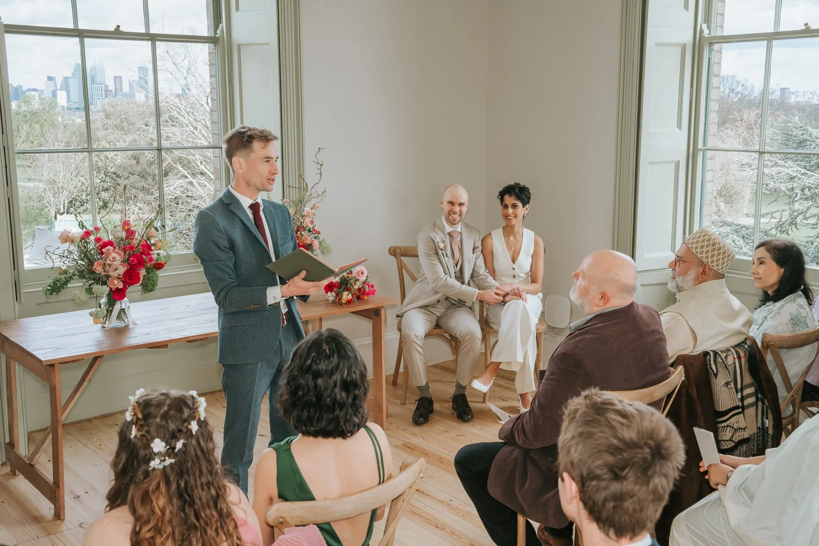  Wedding celebrant speaking during ceremony at Brockwell Hall as bride and groom listen, natural light-filled South London venue. 