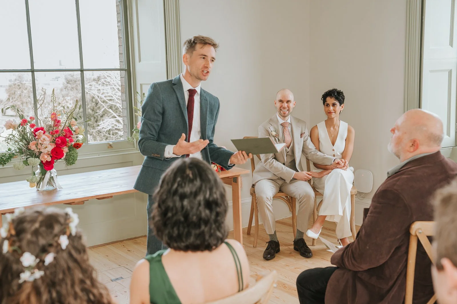  Wedding celebrant speaking during ceremony at Brockwell Hall as bride and groom listen, natural light-filled South London venue. 