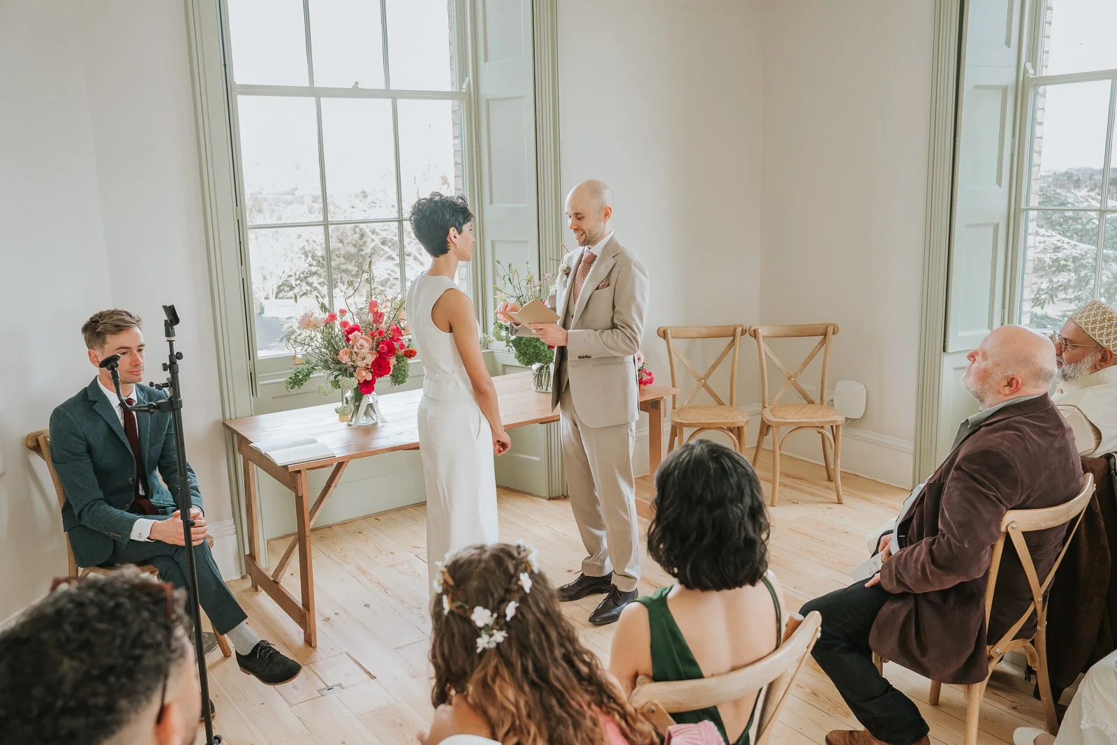  Groom reading vows during ceremony at Brockwell Hall, relaxed indoor wedding with natural light and floral arrangements. 