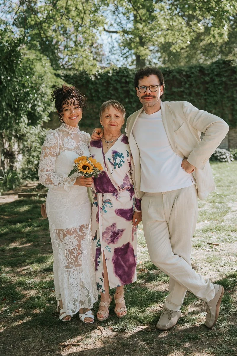  Bride, groom and family member posing together in leafy garden at Tower Hamlets Register Office wedding in East London. 