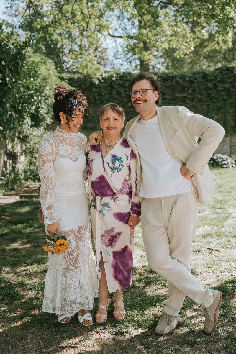  Bride, groom and family member posing together in leafy garden at Tower Hamlets Register Office wedding in East London. 