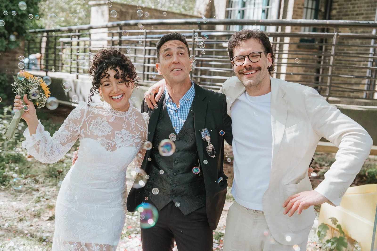  Bride and groom with guest surrounded by bubbles outside Tower Hamlets Register Office after wedding ceremony. 