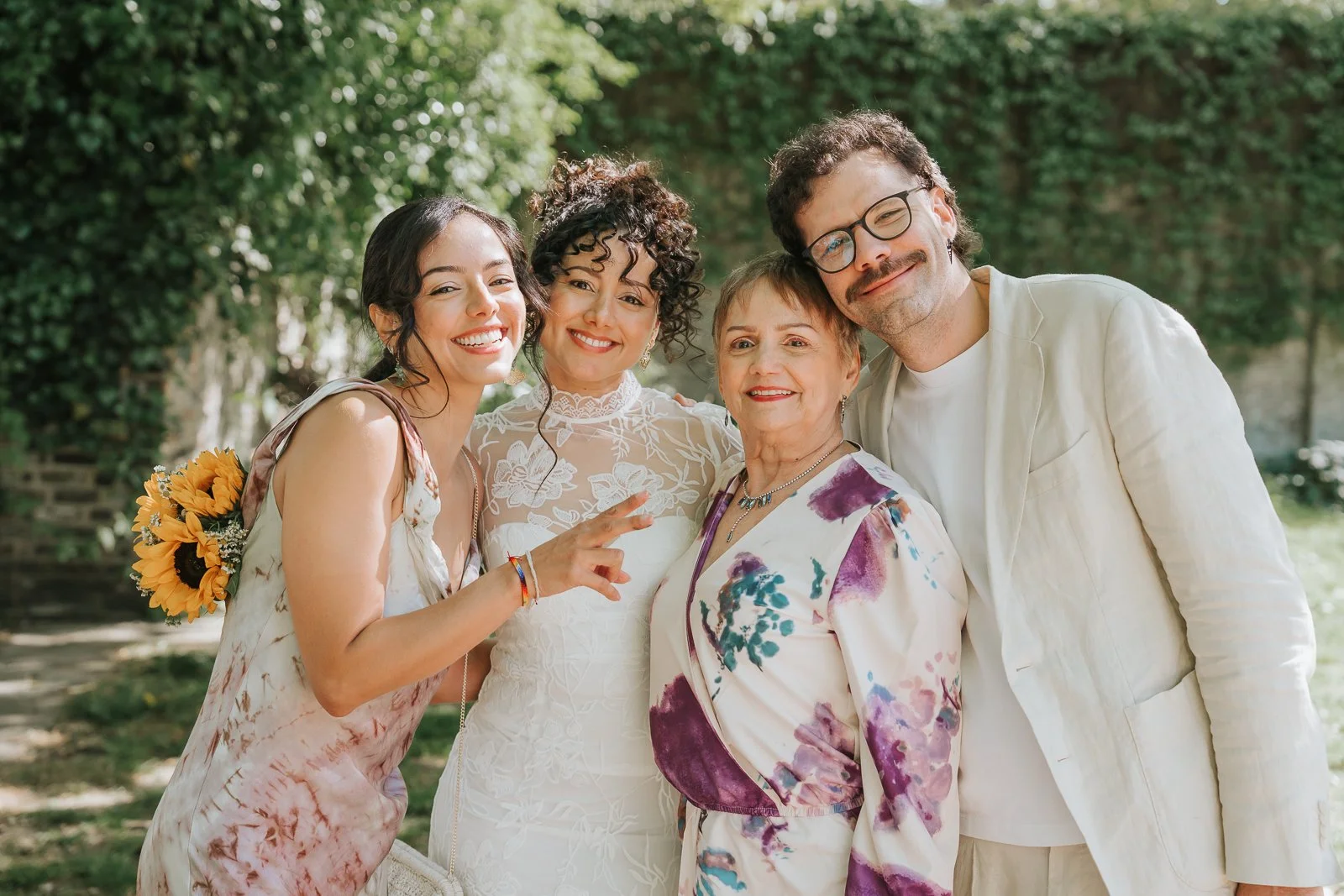  Bride, groom and family smiling together in garden at Tower Hamlets Register Office wedding. 