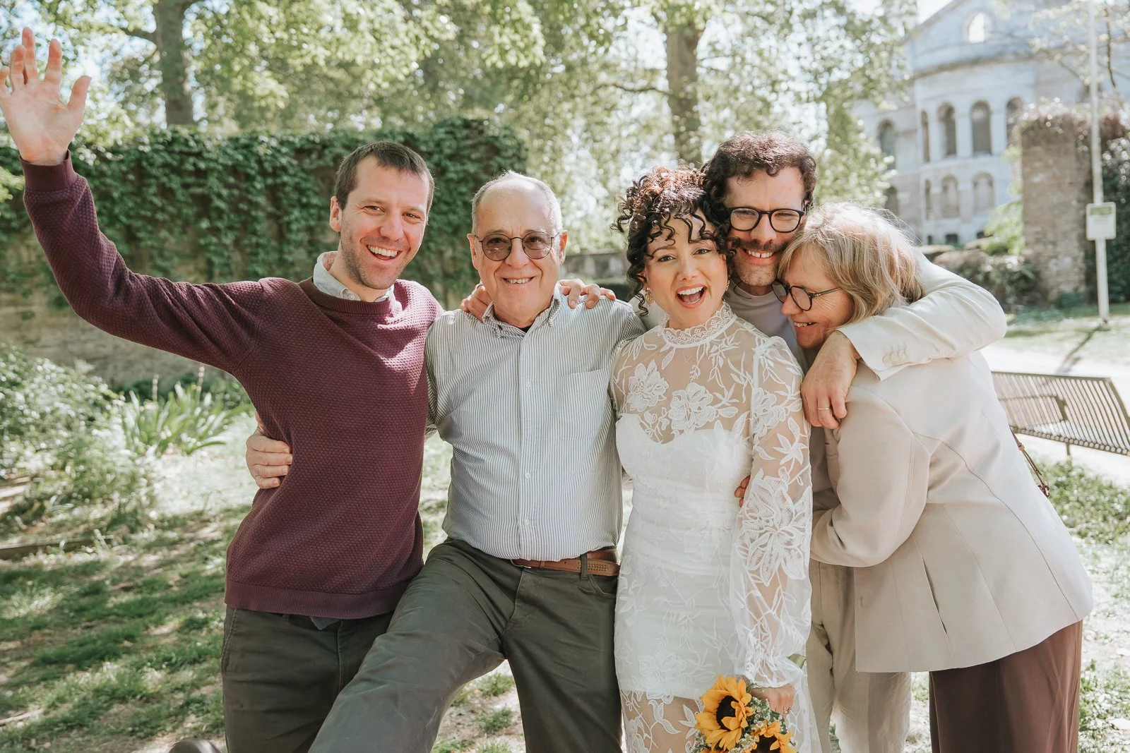  Bride celebrating with family group in sunny garden at Tower Hamlets Register Office East London wedding. 