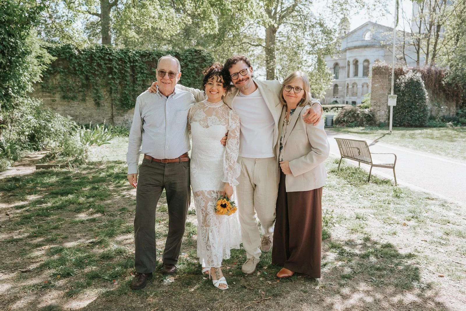  Couple with parents posing in outdoor garden near Tower Hamlets Registry Office London after ceremony. 