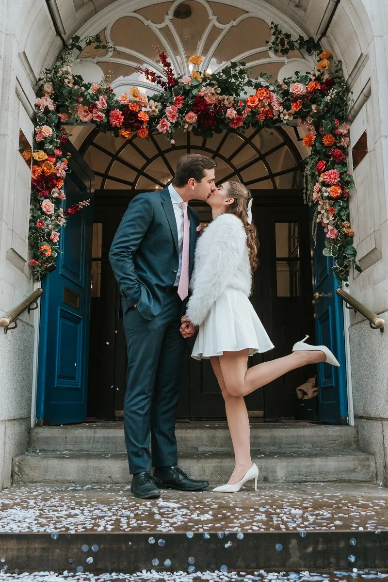  Newly married Bride and Groom pose for a photograph on the steps outside Chelsea Old Town Hall. 