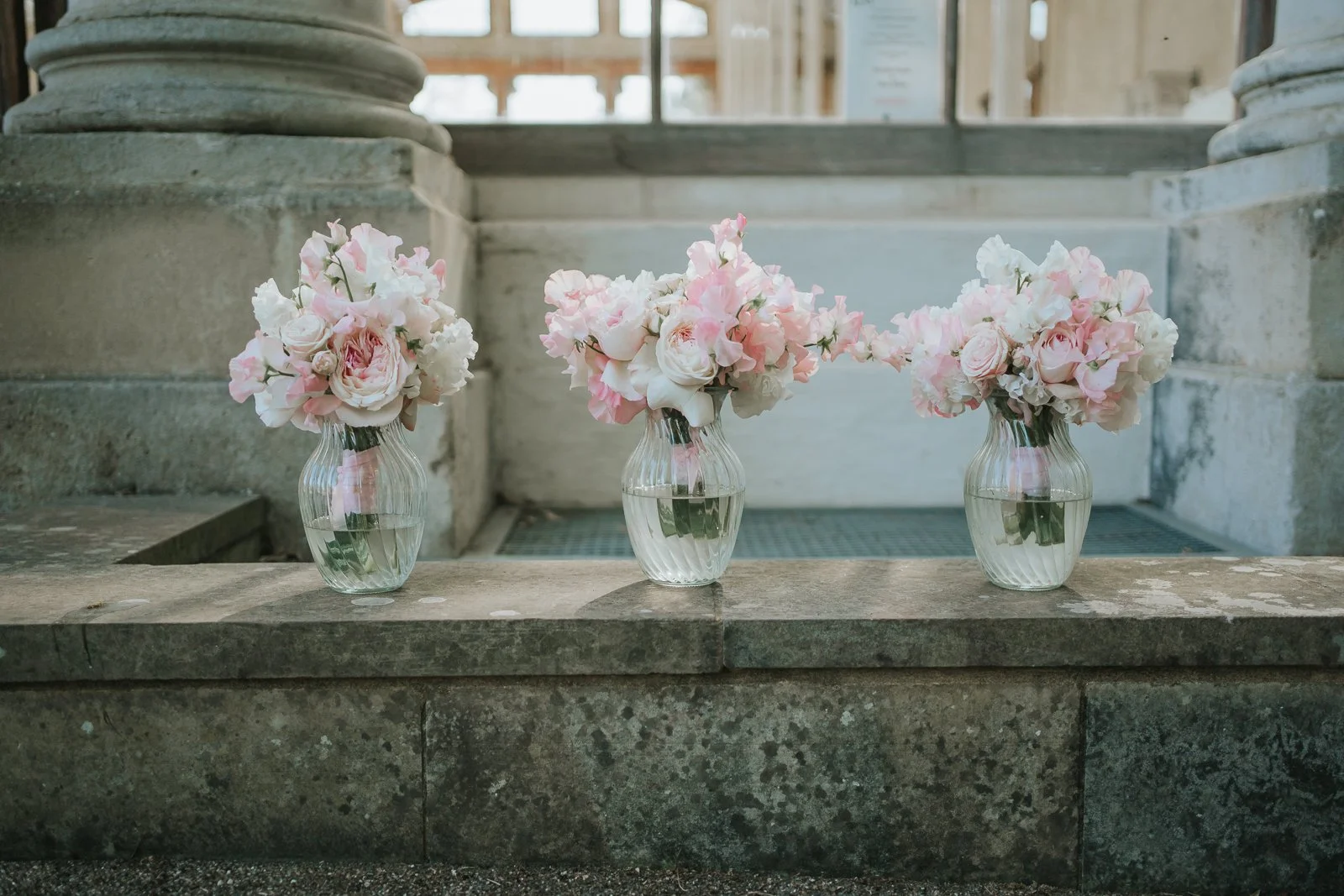  Ceremony floral arrangements in glass vases at The Nash Conservatory wedding venue in Kew Gardens London. 