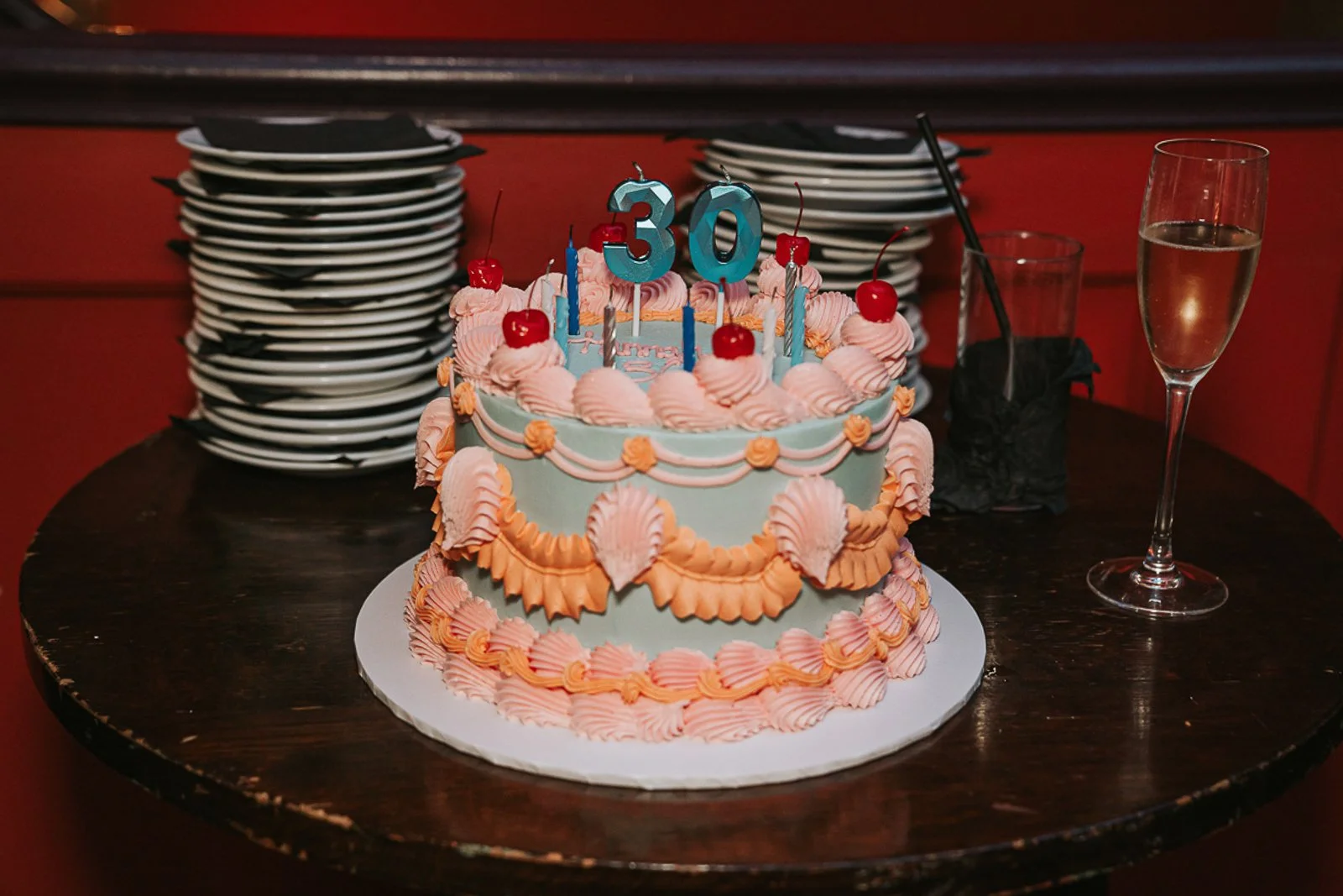  Pastel 30th birthday cake with candles and champagne at a stylish South London birthday party, photographed by a London event photographer. 