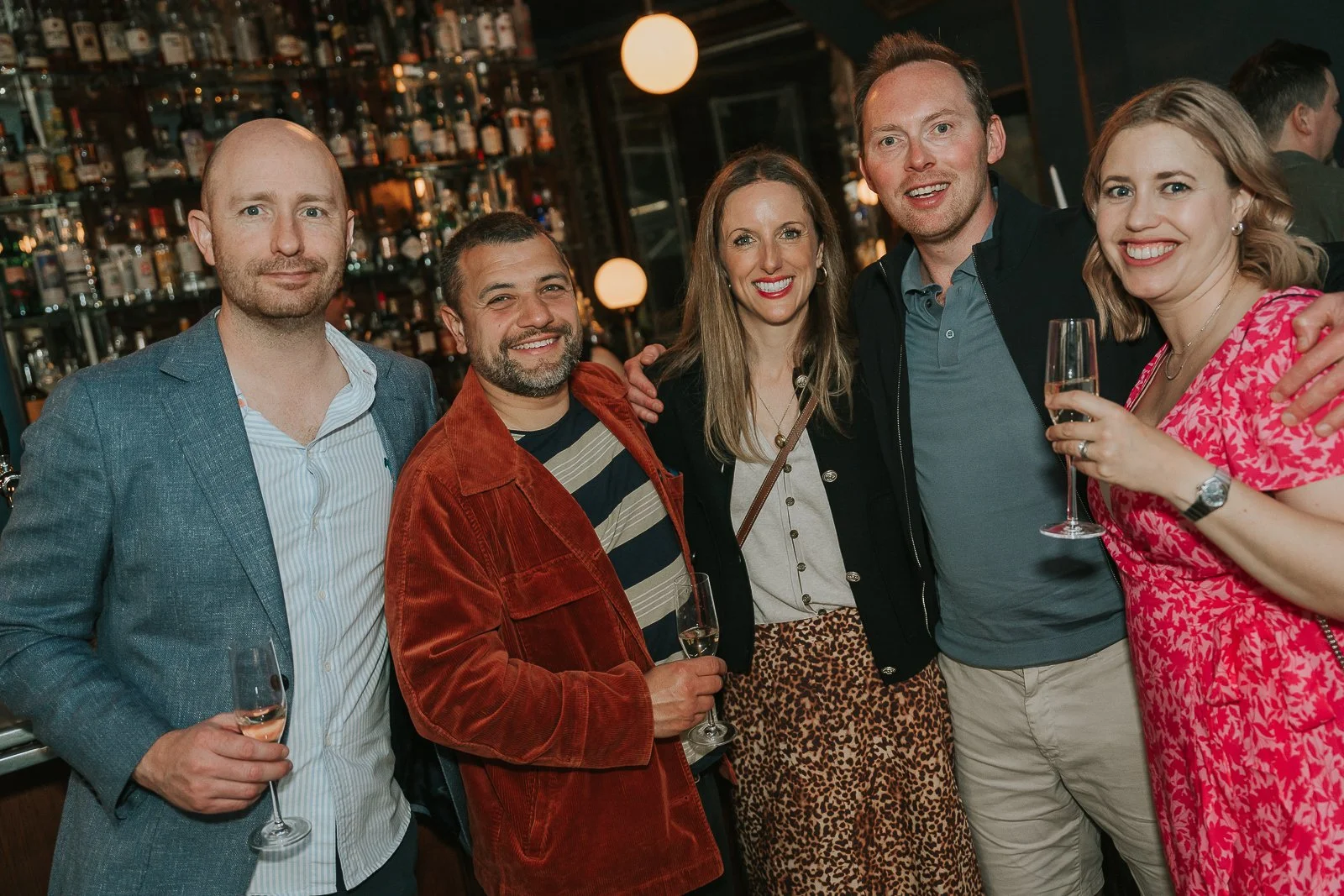  Friends gathered for a group photo at a milestone 40th birthday party, enjoying drinks and celebrating together. 