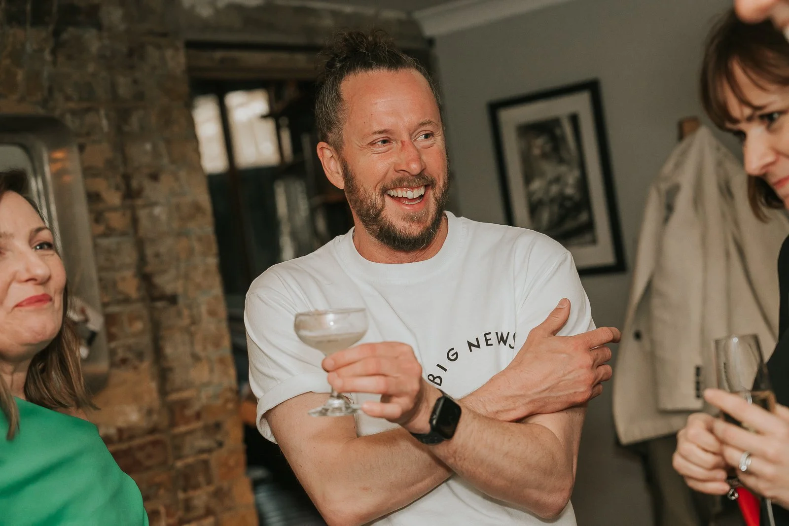  Birthday host laughing with guests over drinks at an intimate 40th birthday party in South London. 
