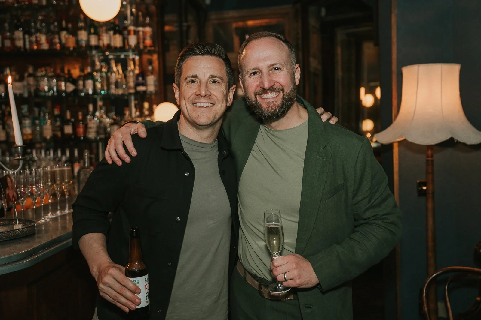  Two friends posing with drinks at a stylish 40th birthday party in South London, photographed in a private bar venue. 