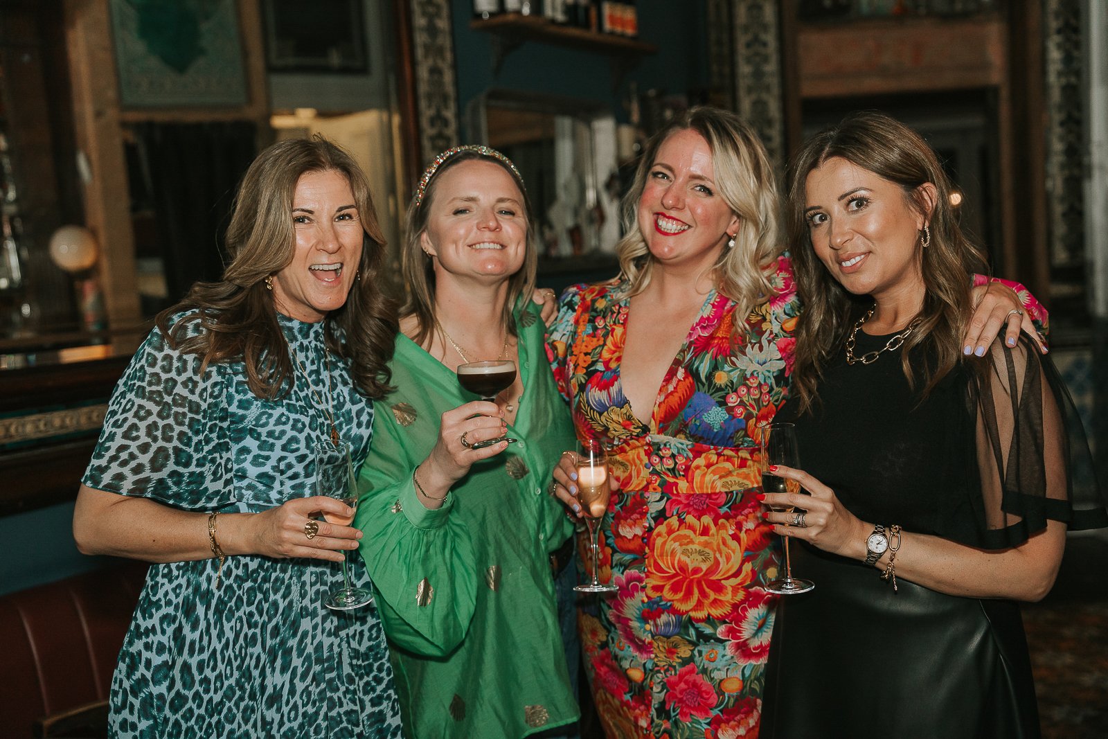  Friends gathered for a group photo at a milestone 40th birthday party, enjoying drinks and celebrating together. 