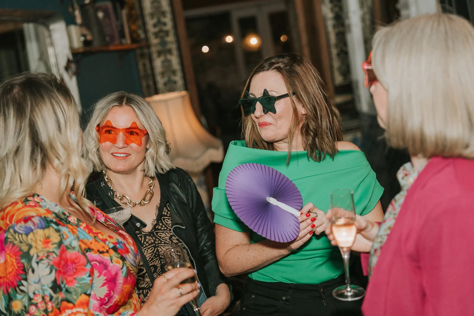 Guests wearing fun party glasses and chatting over drinks at a relaxed 40th birthday celebration in South London. 