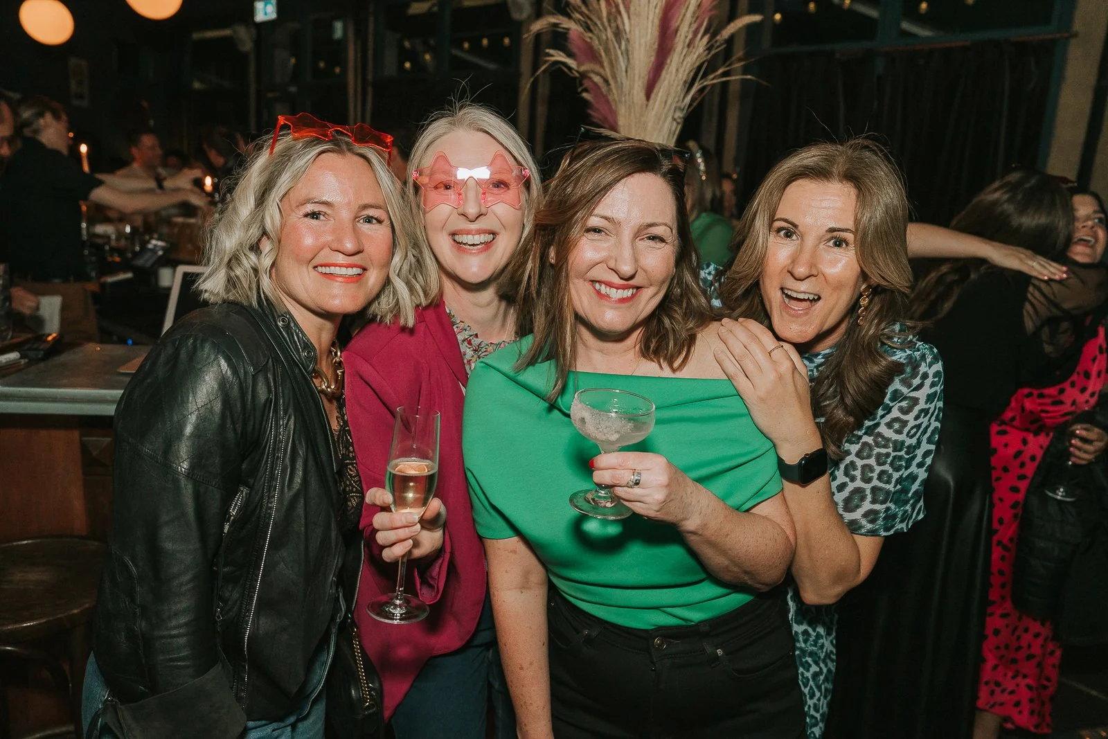  Friends gathered for a group photo at a milestone 40th birthday party, enjoying drinks and celebrating together. 
