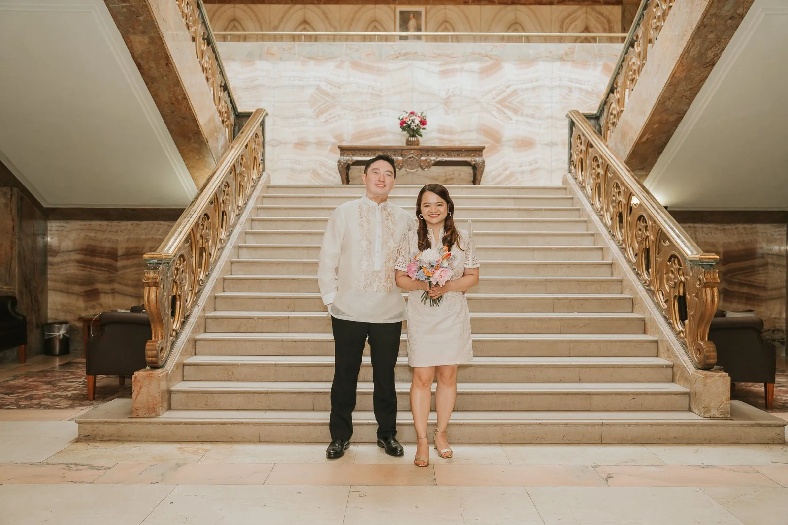  Newly married couple posing on the grand marble staircase in Wandsworth Town Hall's iconic Art Deco atrium after their London registry office wedding. 