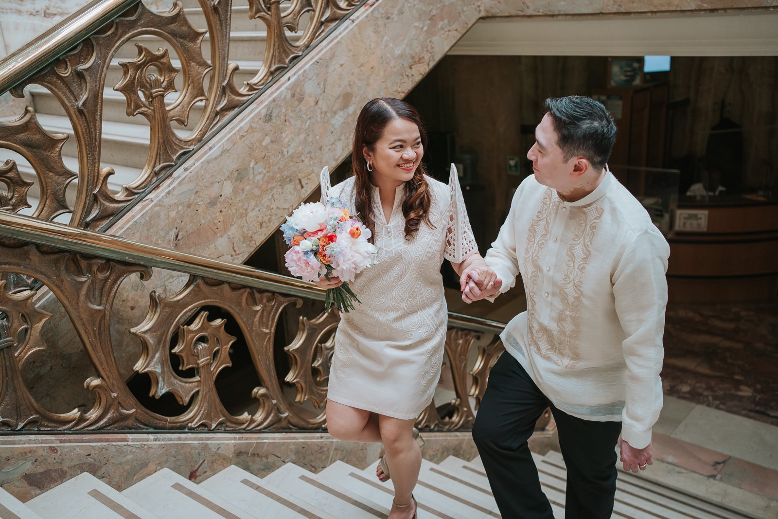  Bride and groom walking hand in hand down the ornate marble staircase at Wandsworth Town Hall, a stunning backdrop for London wedding photography. 