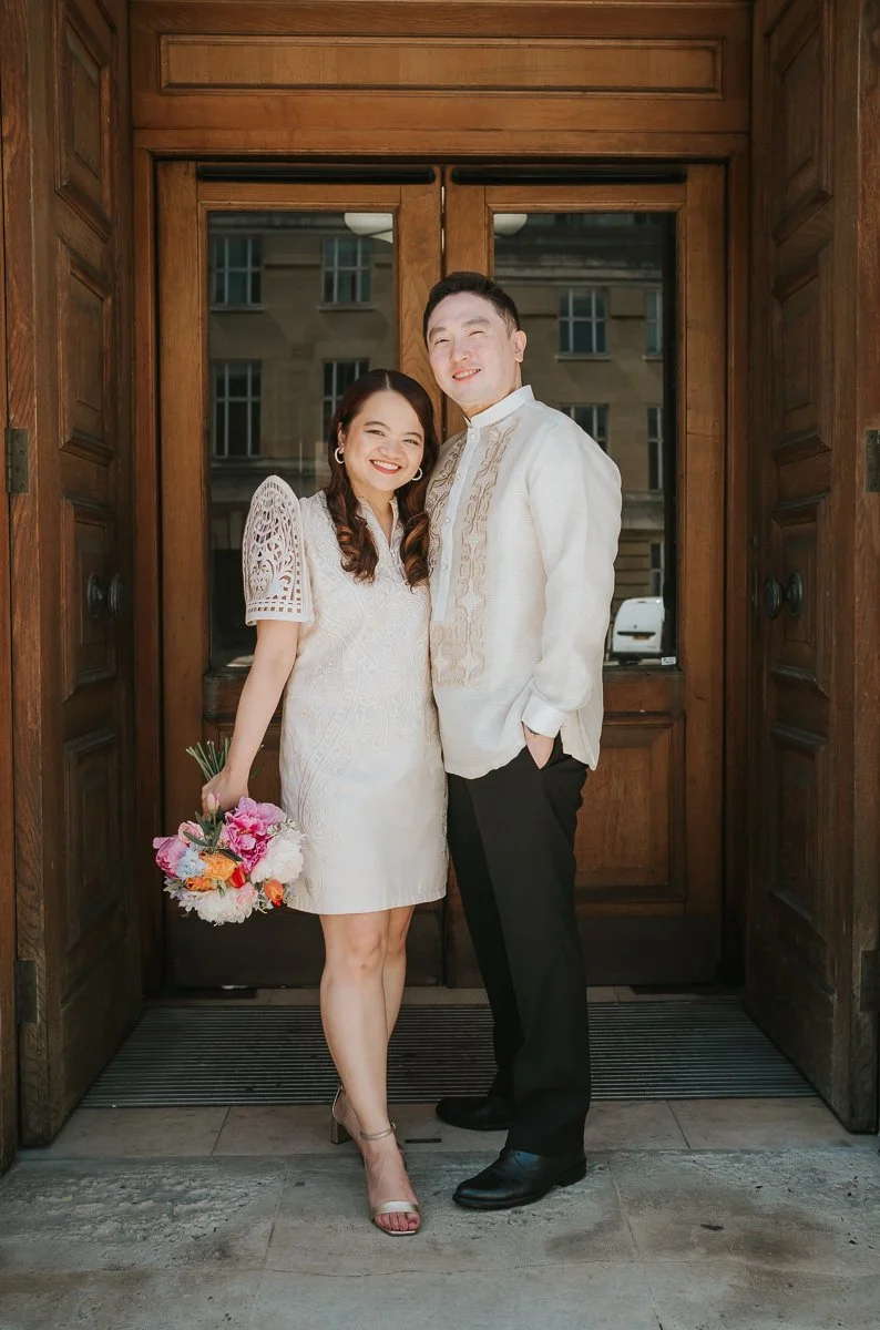  Newly married couple posing in the grand wooden doorway of Wandsworth Town Hall after their intimate London registry office wedding. 