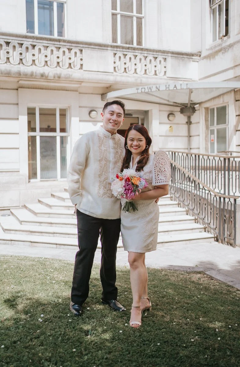  Newly married couple posing outside Wandsworth Town Hall after their intimate London registry office wedding. 