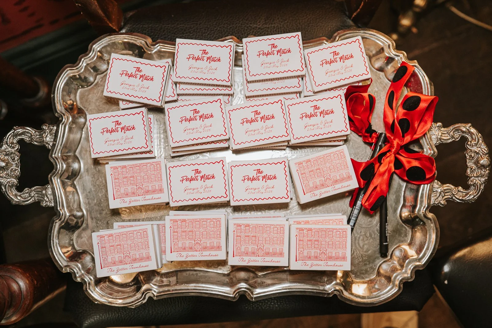  Personalised wedding matchbox favours arranged on an ornate silver tray with red ribbon details at The Zetter Townhouse Clerkenwell. 