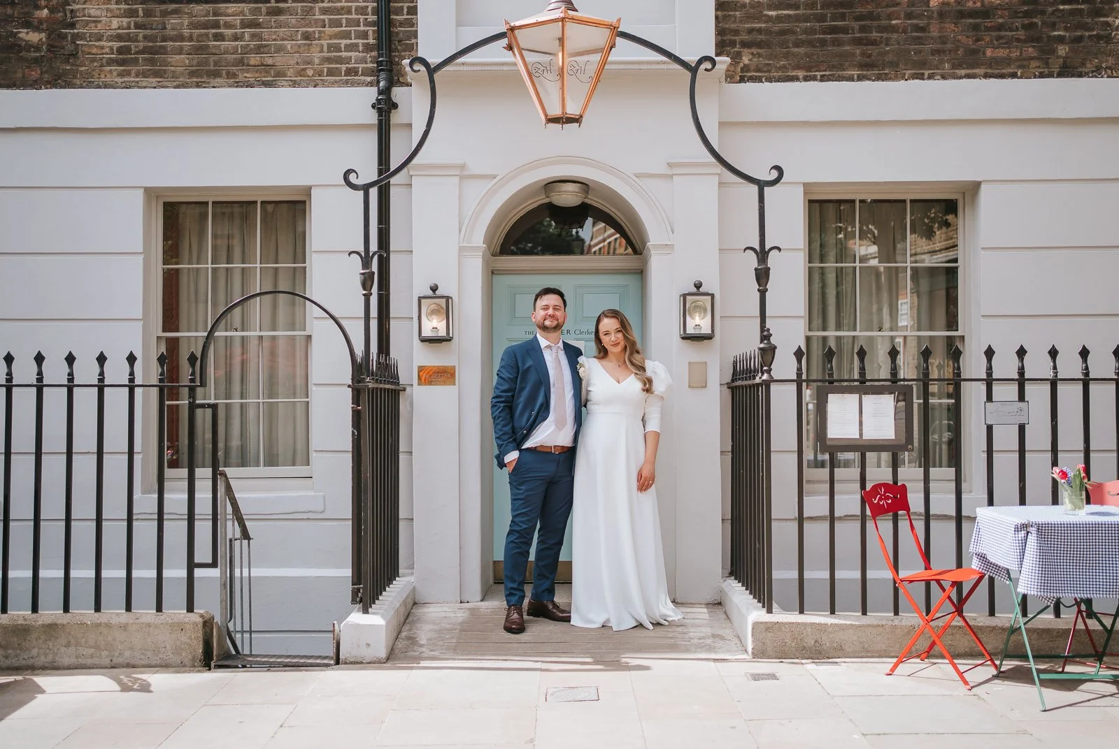  Newlywed couple posing outside the entrance of The Zetter Townhouse Clerkenwell, a stylish and intimate London wedding venue in Clerkenwell. 