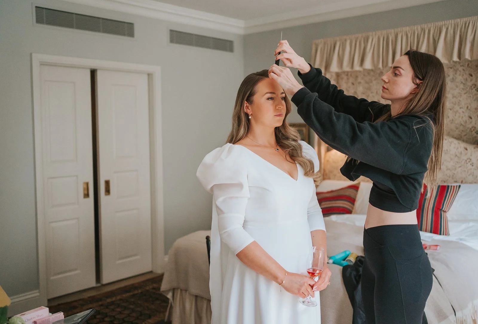  Bride getting ready in one of The Zetter Townhouse Clerkenwell's stylish bedrooms, with a family member fastening her elegant wedding dress. 