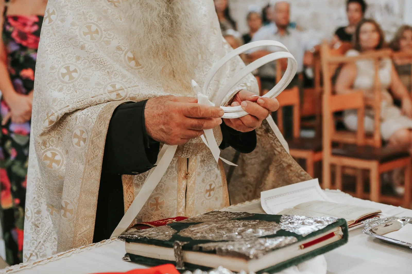  Greek Orthodox priest preparing the wedding crowns and ceremonial items on the altar table during a traditional Orthodox wedding ceremony in a London Greek church. 