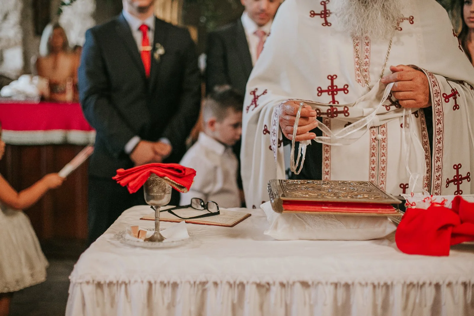  Greek Orthodox priest preparing the wedding crowns and ceremonial items on the altar table during a traditional Orthodox wedding ceremony in a London Greek church. 