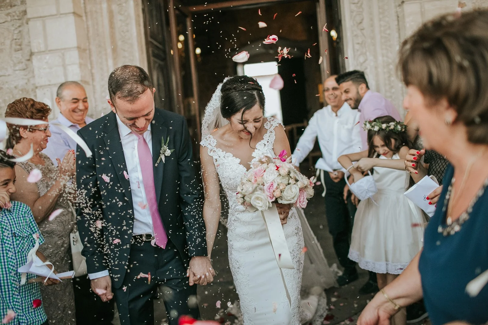  Bride and groom walking through a shower of rose petals and confetti outside a Greek Orthodox church in London after their wedding ceremony. 