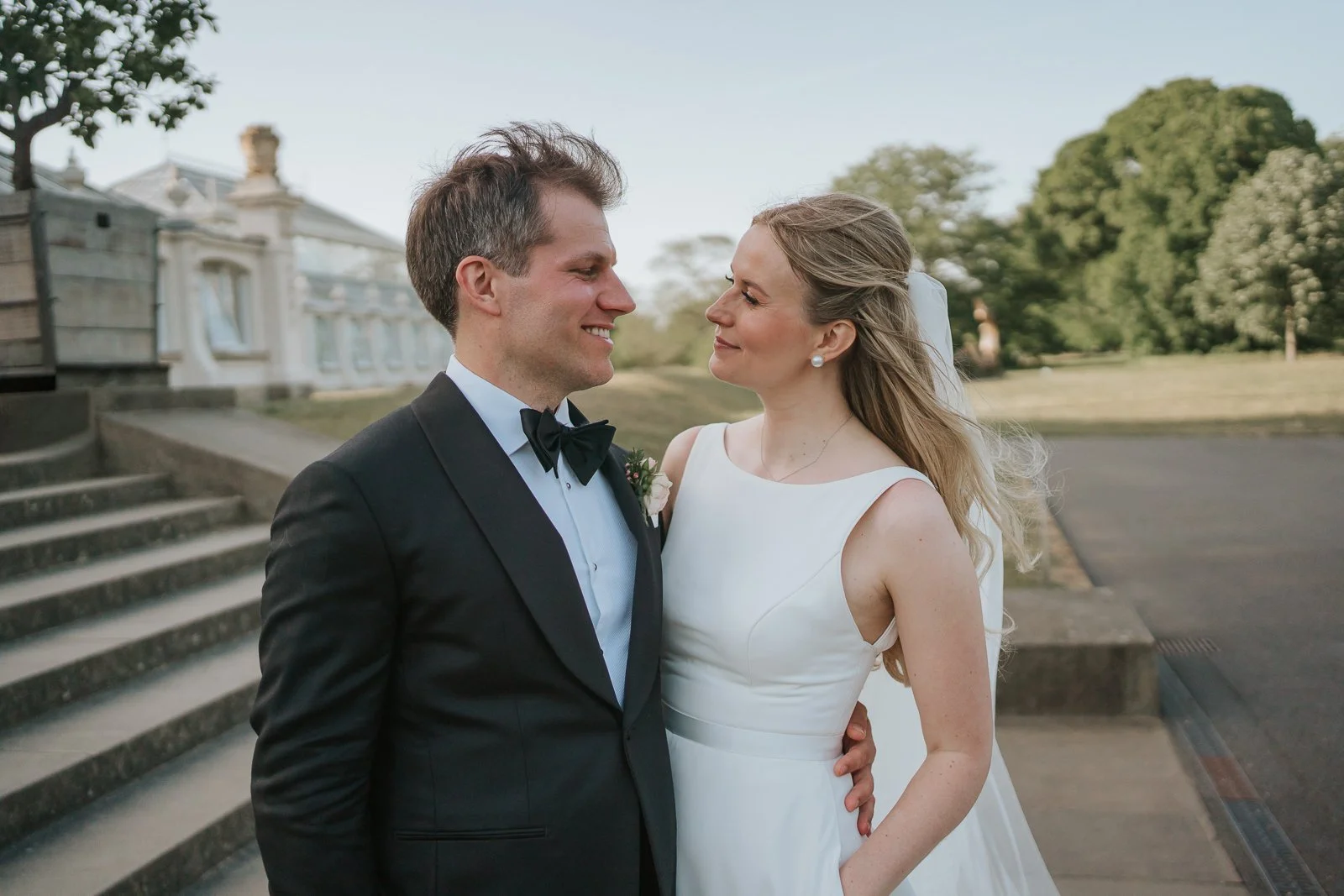  Newlyweds sharing a quiet moment outside the Temperate House at Kew Gardens, captured by a Kew Gardens wedding photographer against the iconic glasshouse backdrop. 