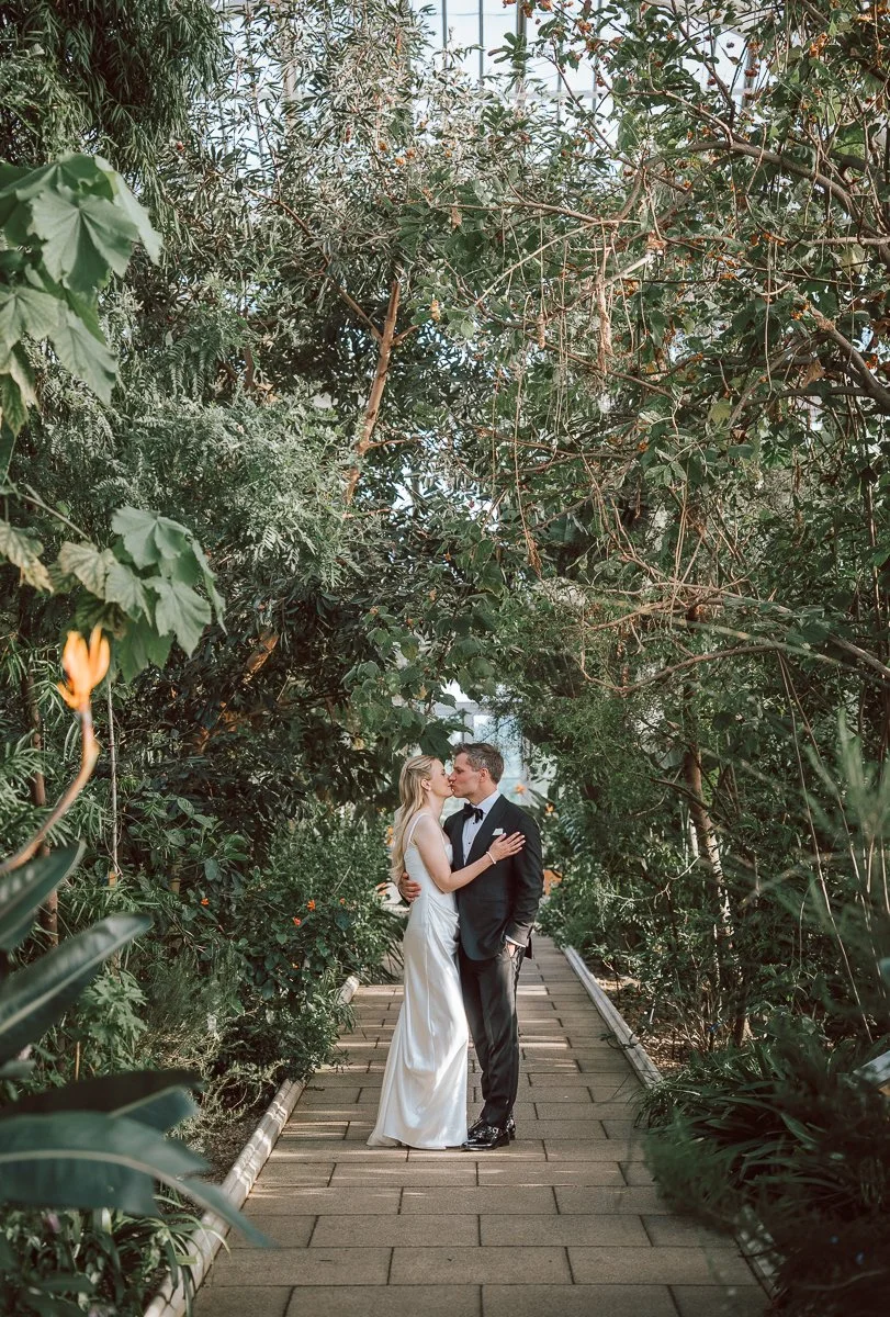 Romantic wedding portrait inside the Temperate House at Kew Gardens, surrounded by towering greenery and exotic plants. 