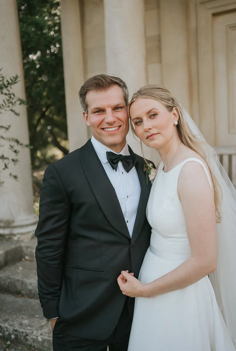  Bride and groom embracing at King William’s Temple in Kew Gardens, framed by elegant Georgian architecture and soft natural light. 