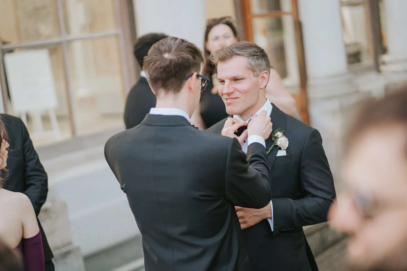  Groom adjusting his bow tie with the help of a groomsman outside the Nash Conservatory at Kew Gardens before the wedding ceremony. 