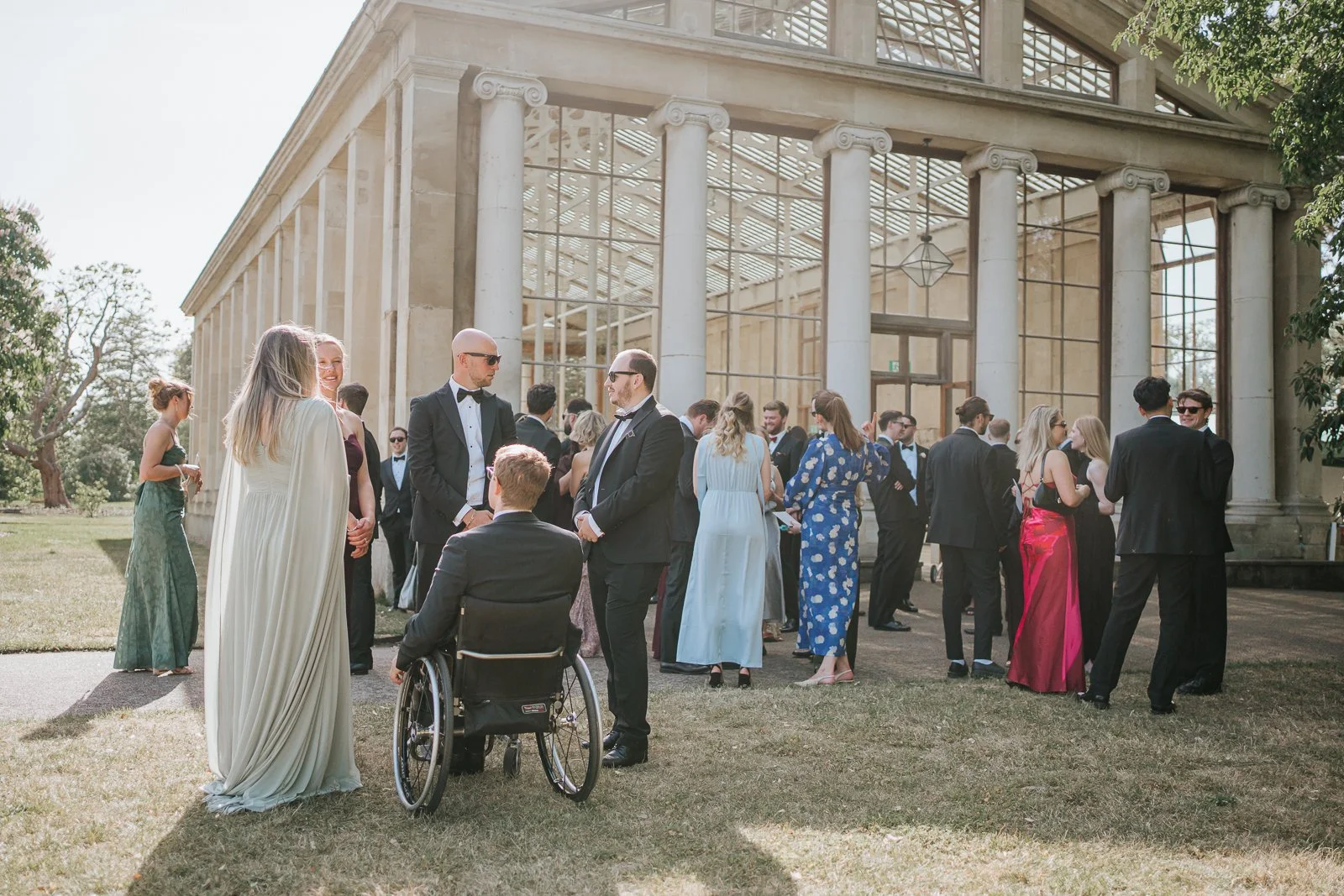  Wedding guests enjoying drinks and conversation on the lawn outside the Nash Conservatory at Kew Gardens before the ceremony begins. 