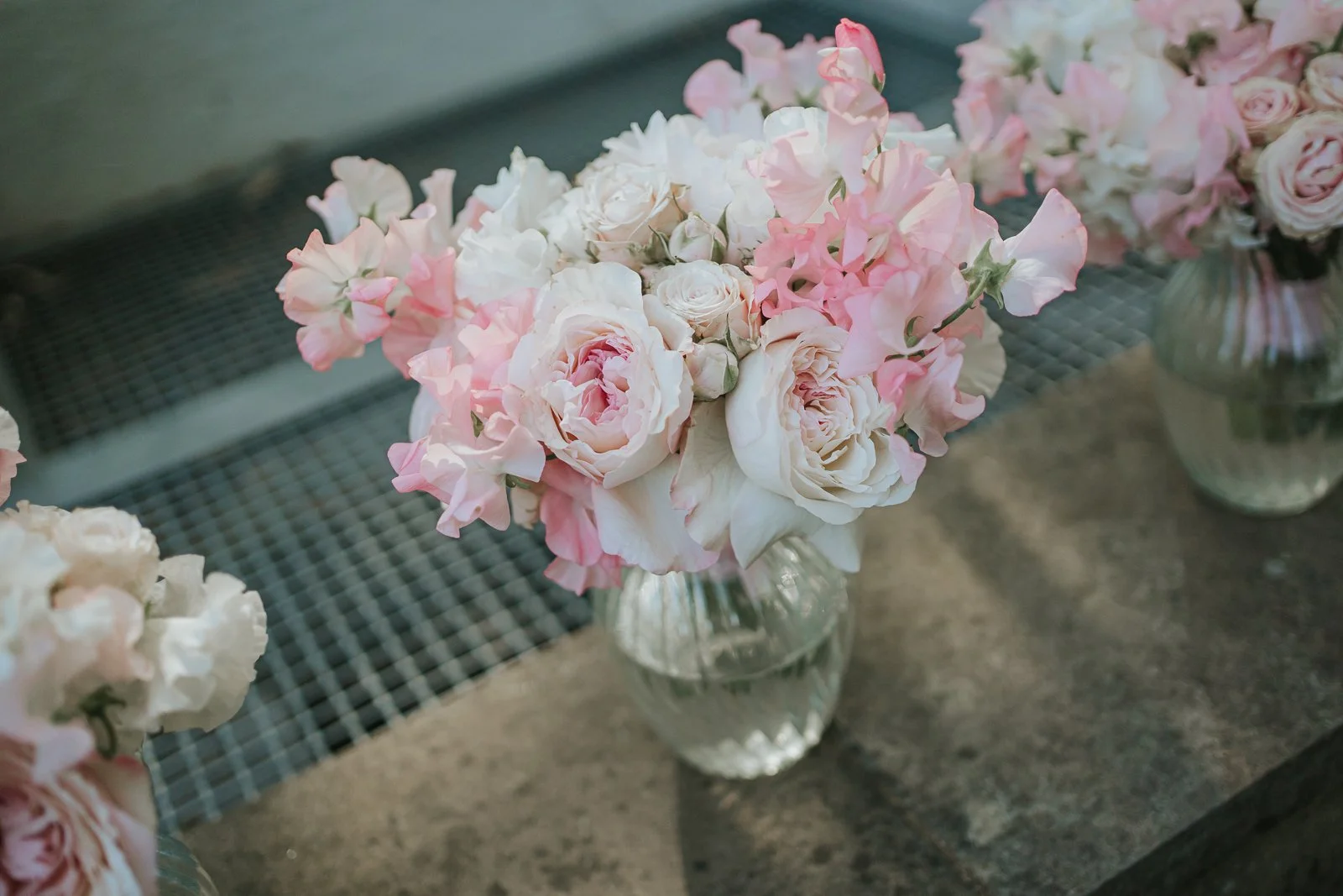  Elegant wedding flowers featuring blush roses and pink sweet peas arranged in glass bud vases at the Nash Conservatory, Kew Gardens. 