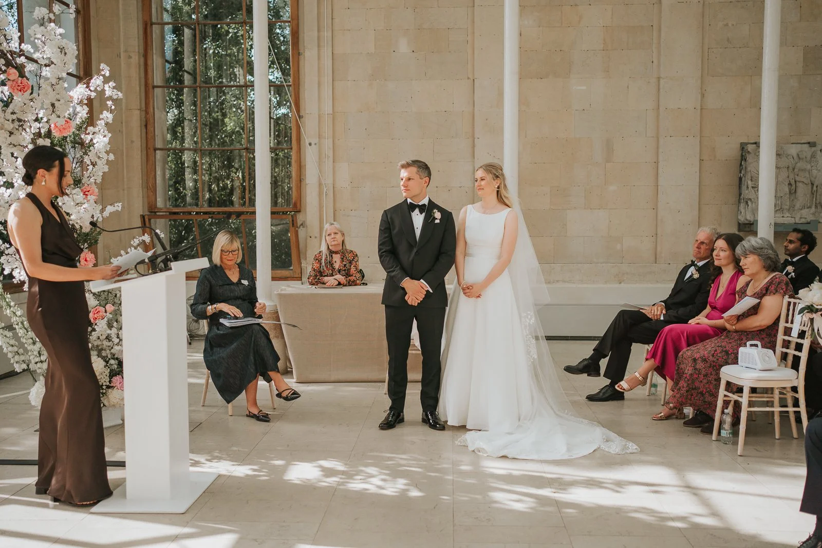  Wedding reading inside the Nash Conservatory at Kew Gardens, with the bride and groom standing together before their guests. 