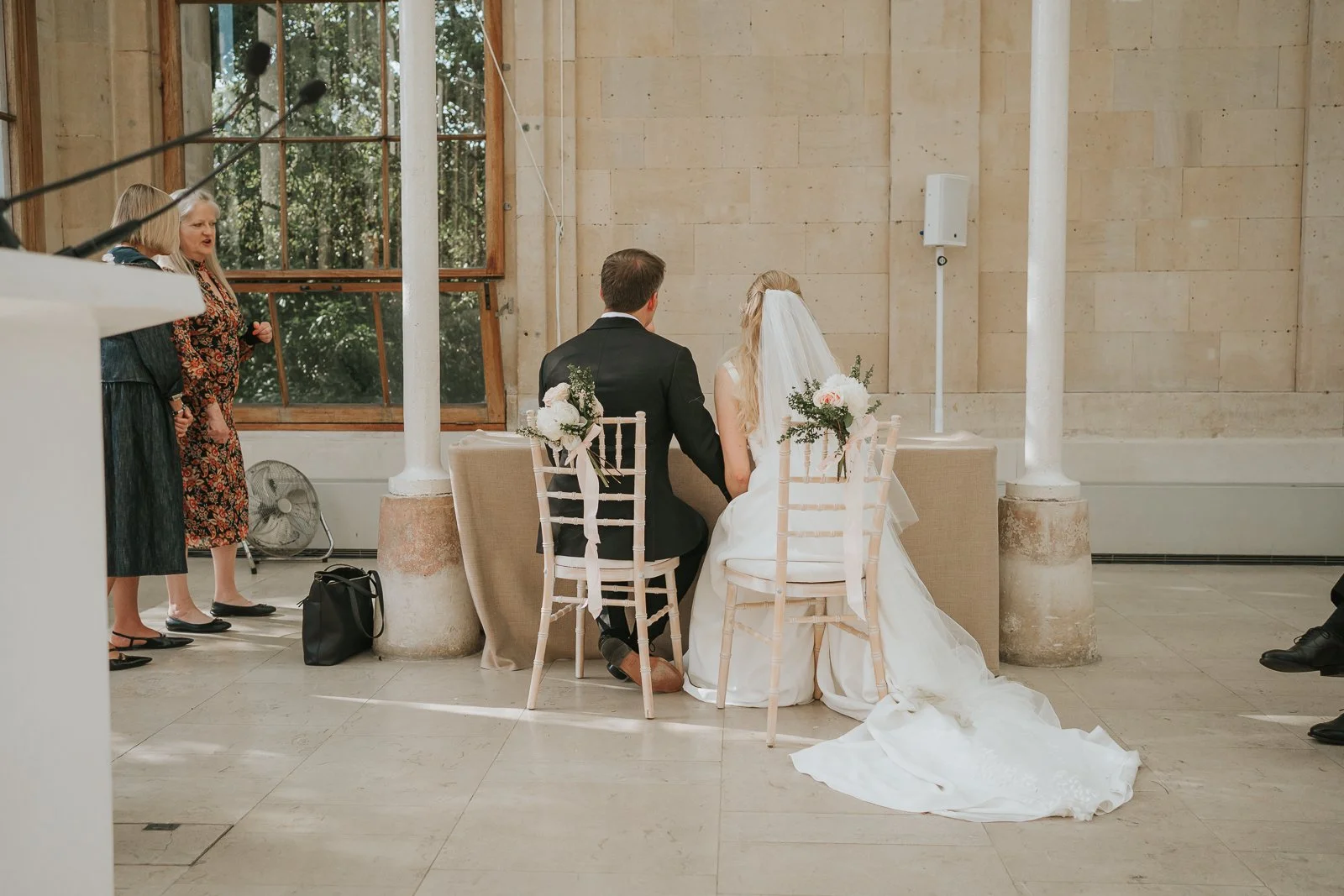  Newly married couple signing the register inside the Nash Conservatory at Kew Gardens with family members looking on. 
