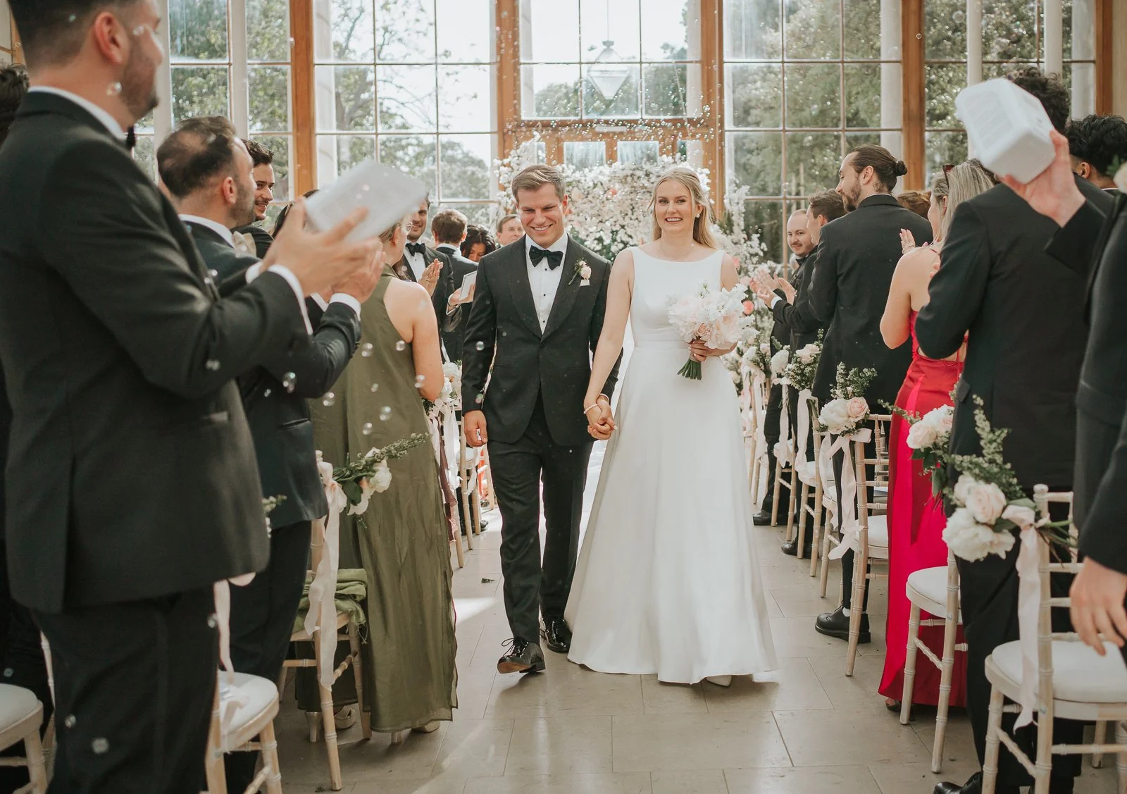  Newlyweds walking back down the aisle through bubbles and applause after their wedding ceremony at the Nash Conservatory. 