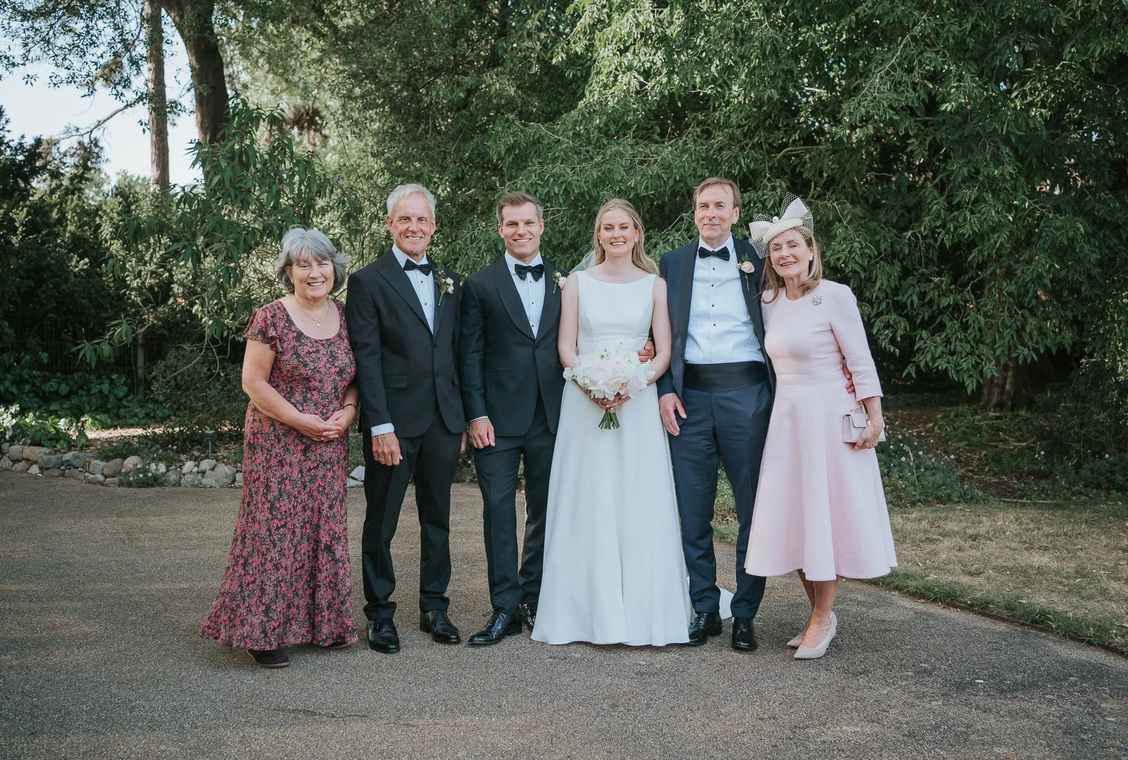  Newlyweds posing with parents for a relaxed family photograph in the gardens at Kew Gardens after their wedding. 