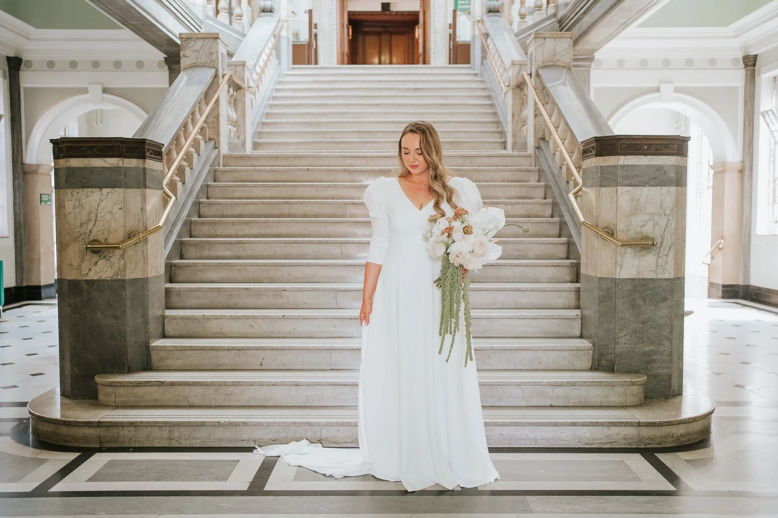  Bride holding a cascading bouquet on the iconic marble staircase inside Islington Town Hall. 
