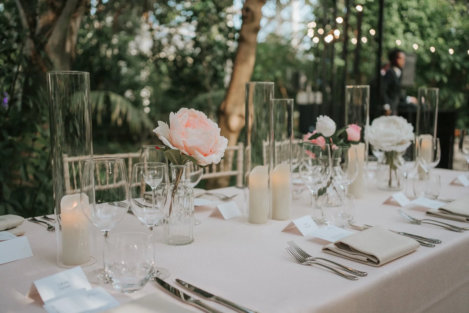  Romantic wedding table details inside the Temperate House at Kew Gardens with soft floral arrangements, candles and tropical foliage creating a magical atmosphere. 