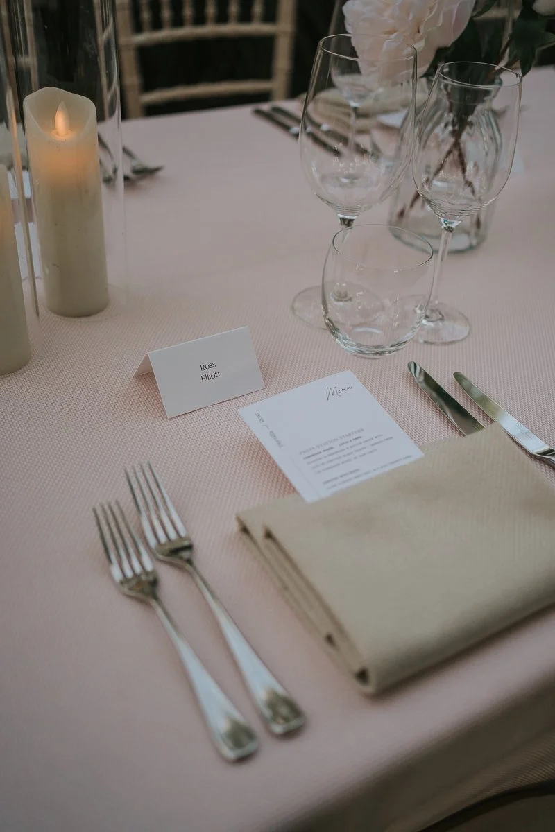  Elegant wedding place setting with candlelight, glassware and personalised name cards inside the Temperate House at Kew Gardens. 