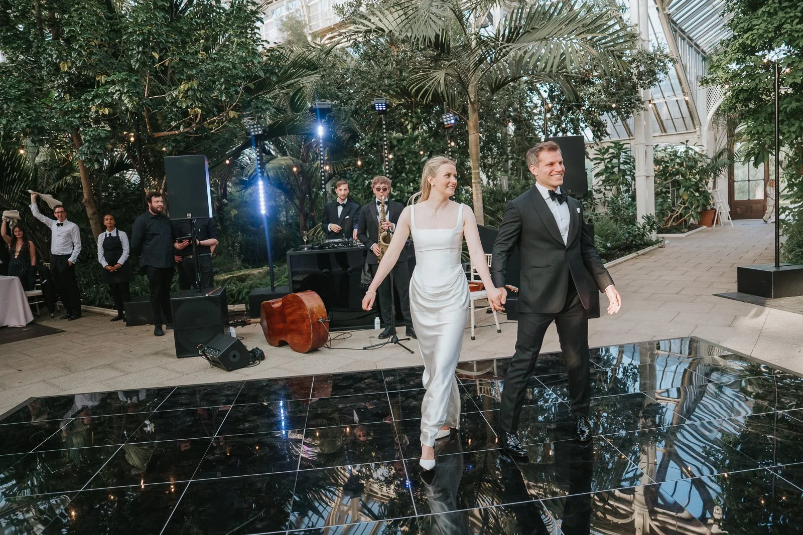  Newlyweds making their grand entrance onto the dance floor inside the Temperate House at Kew Gardens, with live music and lush botanical surroundings. 