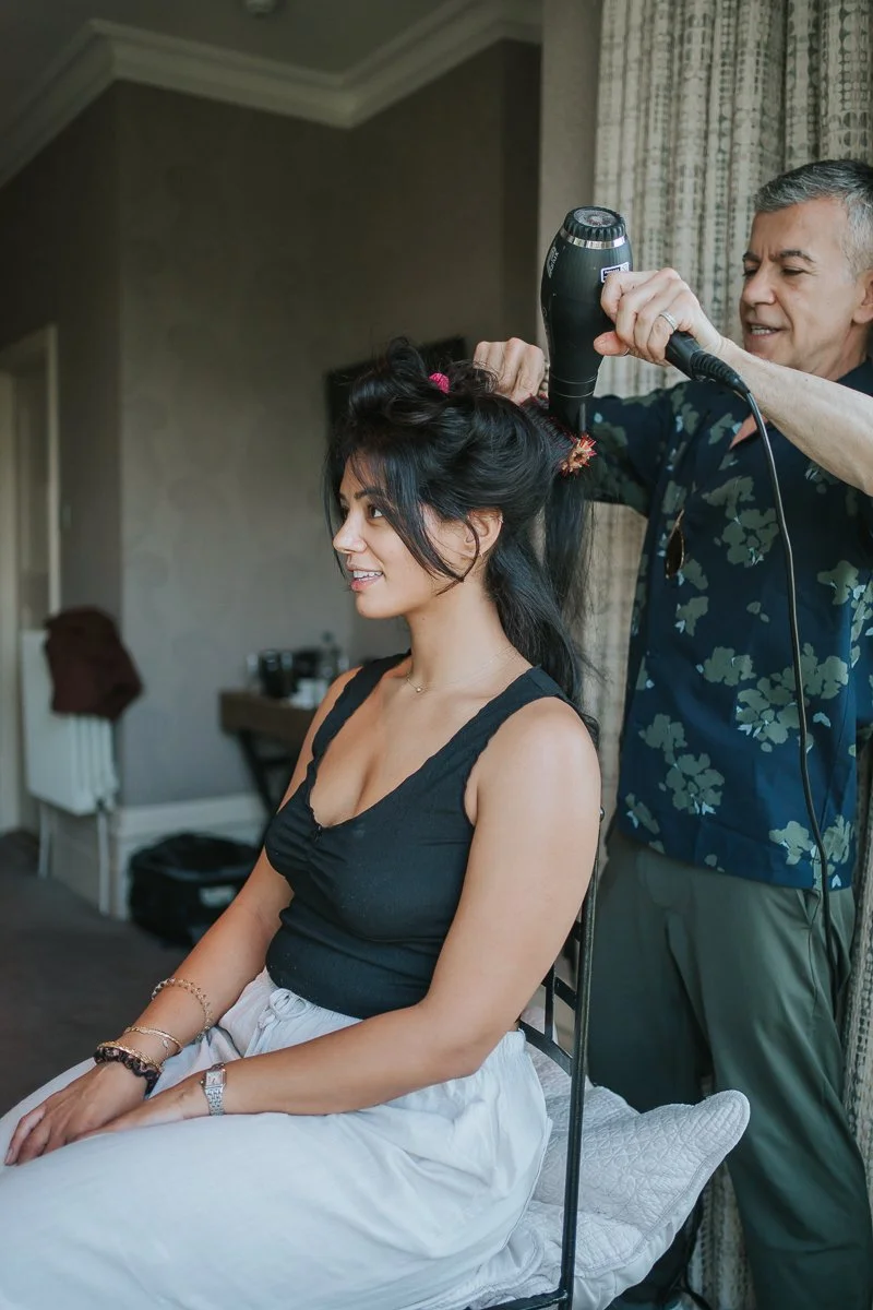  Bridesmaid having her hair styled by a hairstylist in a hotel suite at The Petersham Hotel before a Richmond wedding celebration. 