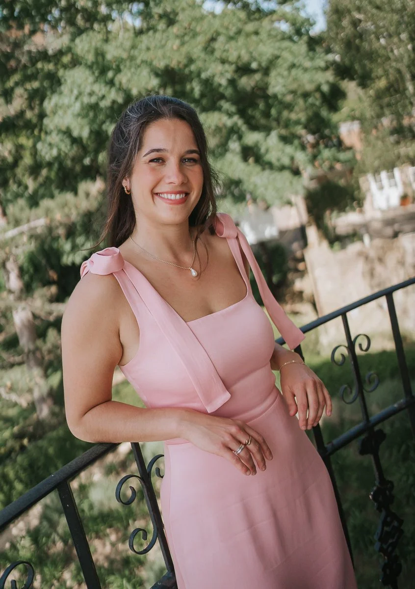  Bridesmaid in a pale pink dress standing on a terrace at The Petersham Hotel, enjoying views of the surrounding greenery before the wedding ceremony.   