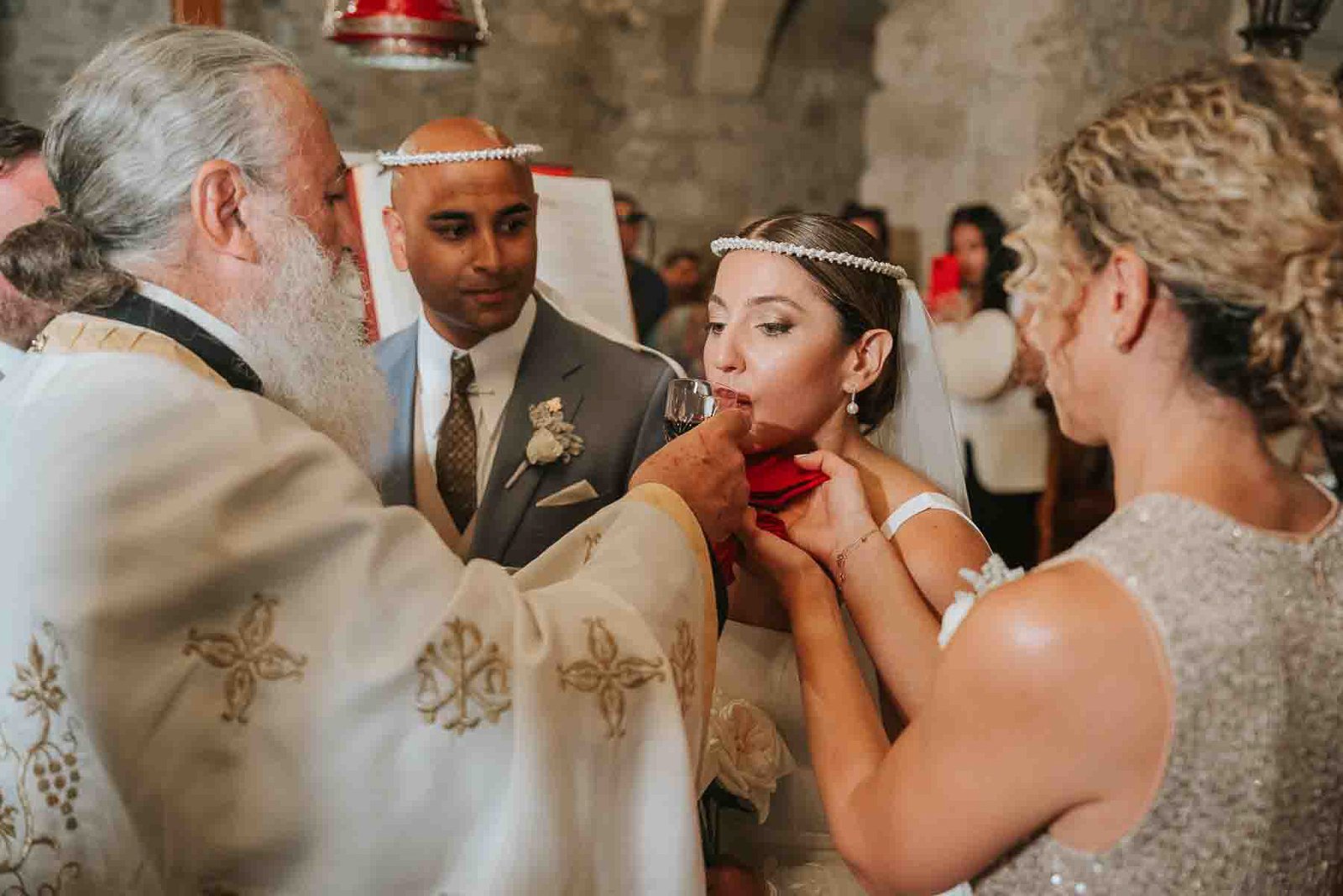  Bride taking part in the ceremonial shared wine ritual during a traditional Greek Orthodox wedding service. 